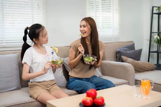 A cheerful interaction as a mother and daughter share healthy foods, conveying warmth and joy in a vibrant domestic setting.