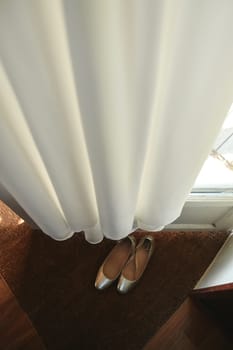 The Wedding dress hanging on the door and golden shoes