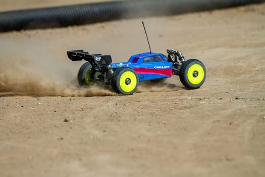 September 11, 2016 - Boise, Idaho: A blue and red toy car is driving on a sandy surface. The car is yellow and has a remote control