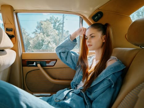Pensive young woman in casual denim attire, sitting in a vintage car, reflecting on life. Bright daylight enhances the mood, perfect for lifestyle and fashion themes.