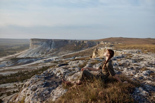 Tranquil woman contemplating majestic mountain range from cliff edge in valley with travel adventure and exploration theme