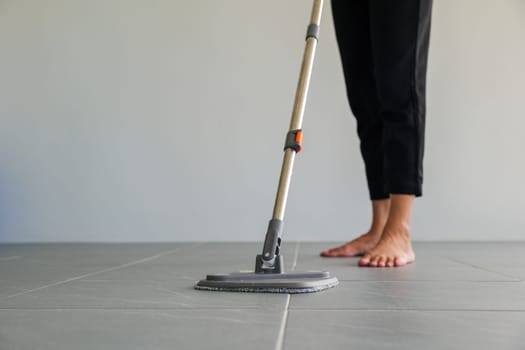 Woman mops the indoor floor, cleaning the front area of her home with a mop and rag. Housewife dedicated to maintaining cleanliness. Represents professional housekeeping and house maintenance concepts