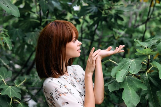 Serene woman connecting with nature, touching leaves on a tree in peaceful contemplation