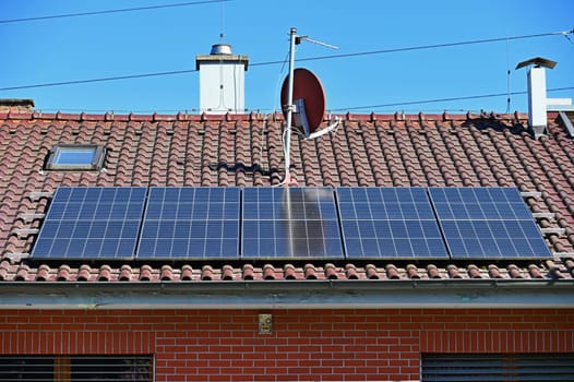 Family house with solar panels on the roof. Home photovoltaic power plant. Concept for industry and green cheaper electricity from renewable sources.