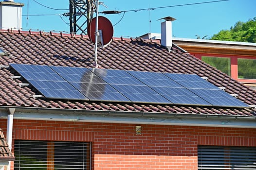 Family house with solar panels on the roof. Home photovoltaic power plant. Concept for industry and green cheaper electricity from renewable sources.