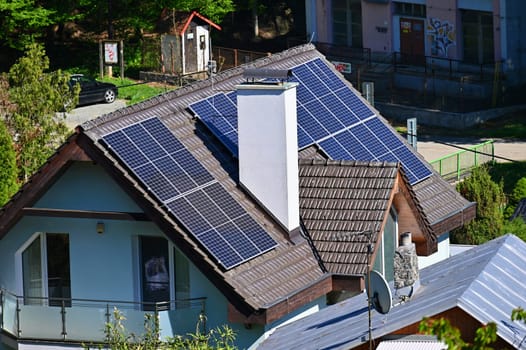 Family house with solar panels on the roof. Home photovoltaic power plant. Concept for industry and green cheaper electricity from renewable sources.