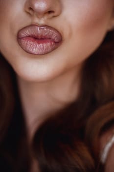 Cropped of woman face, showcasing her lips as they pout in a slightly seductive expression. Closeup view of beautiful woman puckering lips for kiss.