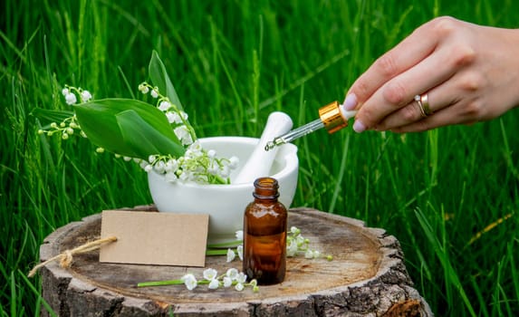 Glass bottle of lily of the valley essential oil with fresh flowers