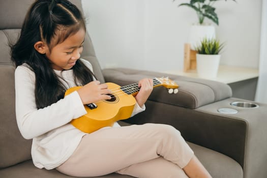 Portrait of an Asian girl on a sofa strumming a ukulele. She wears a white shirt, surrounded by soft lighting and stylish home decor, capturing a serene and artistic moment at home.
