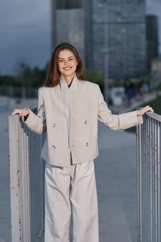 confident woman in beige business suit smiling outdoors with modern cityscape in background, natural light, and casual professional style.