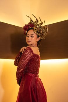 Asian woman in red dress posing with a gold crown on her head inside the studio