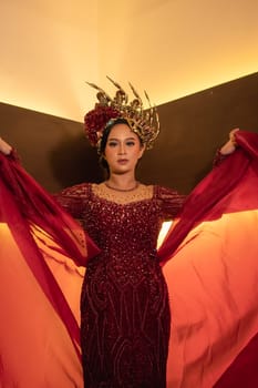 A beautiful Asian woman swings the red fabric tail while wearing a red wedding dress before the wedding ceremony