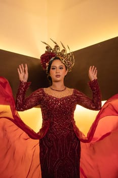 A beautiful Asian woman swings the red fabric tail while wearing a red wedding dress before the wedding ceremony