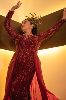 Princess wearing a red dress with the gold crown on her head in front of the lighting in the background