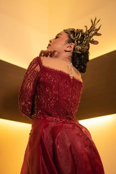 Asian woman in red dress posing with a gold crown on her head inside the studio