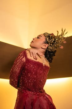 Asian woman in red dress posing with a gold crown on her head inside the studio