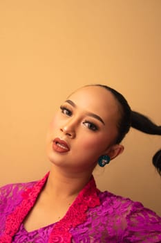 Javanese woman with black hair wearing makeup and a pink dress called kebaya in Indonesia festival event