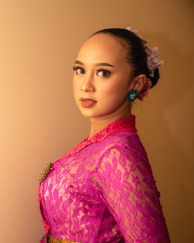 Balinese bride wearing the pink wedding dress before the ceremony has started inside the temple
