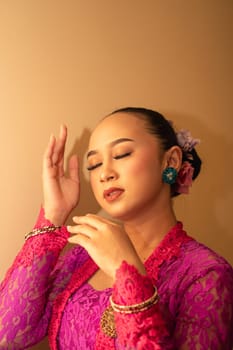 Balinese woman wearing a pink dress during the praying process in the temple at the Bali festival