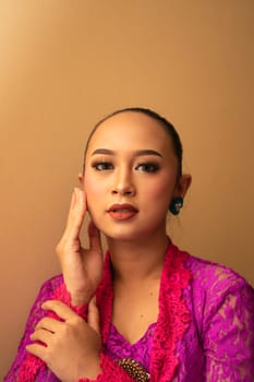 Asian woman touches her head while posing with makeup inside the studio