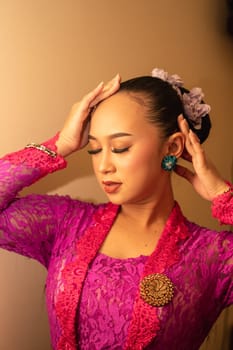 Balinese woman wearing a pink dress during the praying process in the temple at the Bali festival