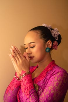 Balinese woman wearing a pink dress during the praying process in the temple at the Bali festival