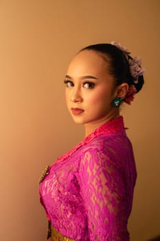Javanese woman with black hair wearing makeup and a pink dress called kebaya in Indonesia festival event