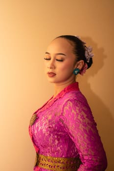 Balinese bride wearing the pink wedding dress before the ceremony has started inside the temple