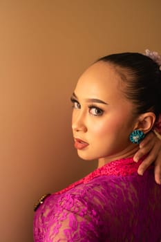 Javanese woman with black hair wearing makeup and a pink dress called kebaya in Indonesia festival event