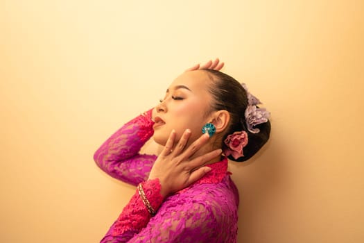 Asian woman touching her neck and feeling sexy with herself while posing inside the cream room