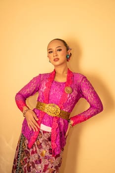 Balinese woman wearing a pink dress called kebaya from Indonesia's traditional dresses inside the temple