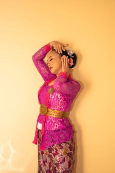 Balinese woman wearing a pink dress called kebaya from Indonesia's traditional dresses inside the temple