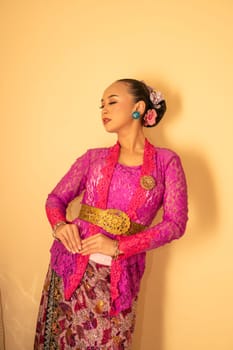 Balinese woman wearing a pink dress called kebaya from Indonesia's traditional dresses inside the temple