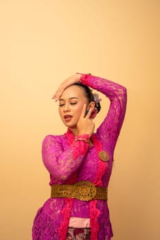 Sexy Asian woman wearing a pink dress called kebaya with a hot pose inside the studio
