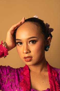 beautiful Balinese woman wearing makeup in a pink dress while posing with exotic hands inside the studio