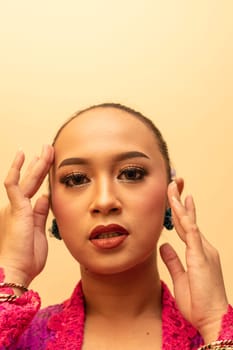 beautiful Balinese woman wearing makeup in a pink dress while posing with exotic hands inside the studio