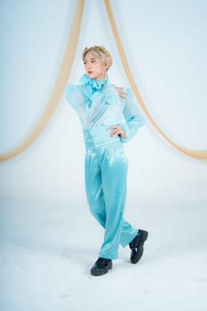 an Asian woman posing elegantly in a blue costume in a white room
