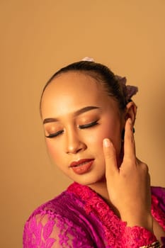 Sexy Asian woman wearing a pink dress called kebaya with a hot pose inside the studio