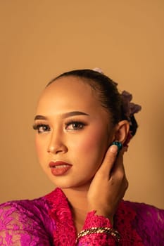 Sexy Asian woman wearing a pink dress called kebaya with a hot pose inside the studio