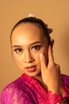Sexy Asian woman wearing a pink dress called kebaya with a hot pose inside the studio