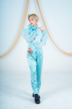 an Asian woman posing elegantly in a blue costume in a white room