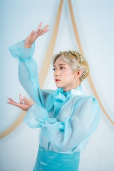 close up photo of an Asian woman with short blonde hair and wearing a blue dress in a white studio