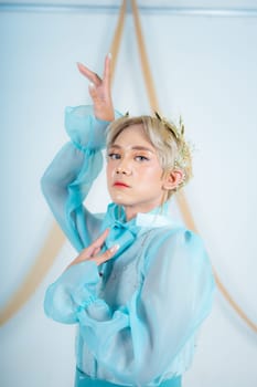 close up photo of an Asian woman with short blonde hair and wearing a blue dress in a white studio