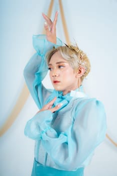 close up photo of an Asian woman with short blonde hair and wearing a blue dress in a white studio