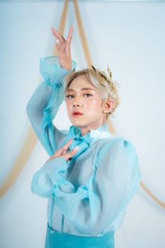 close up photo of an Asian woman with short blonde hair and wearing a blue dress in a white studio