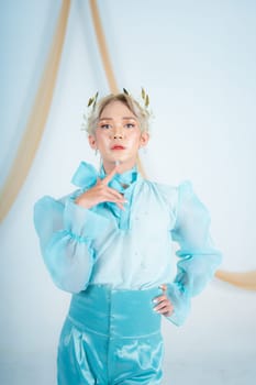 an elegant woman with blonde hair wearing a golden crown and a blue dress in a white room