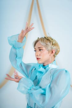 close up photo of an Asian woman with short blonde hair and wearing a blue dress in a white studio