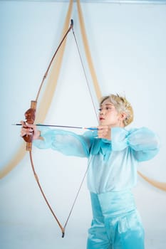 an Asian woman with blonde hair holding an arrow while wearing a blue dress in a white room