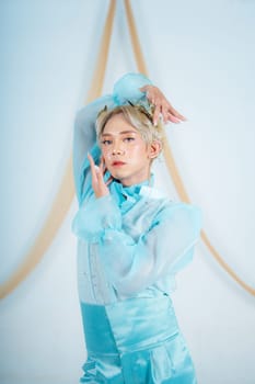 a princess with a blue dress and blonde hair posing very beautifully in front of a white background