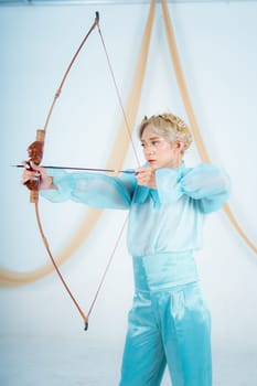 an Asian woman with blonde hair holding an arrow while wearing a blue dress in a white room